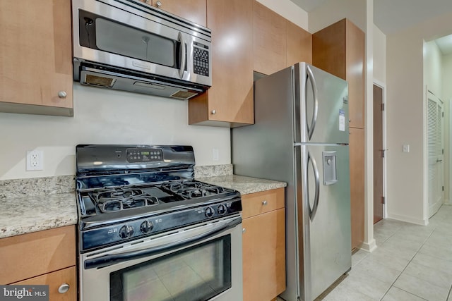 kitchen featuring light tile patterned flooring, light stone countertops, and appliances with stainless steel finishes