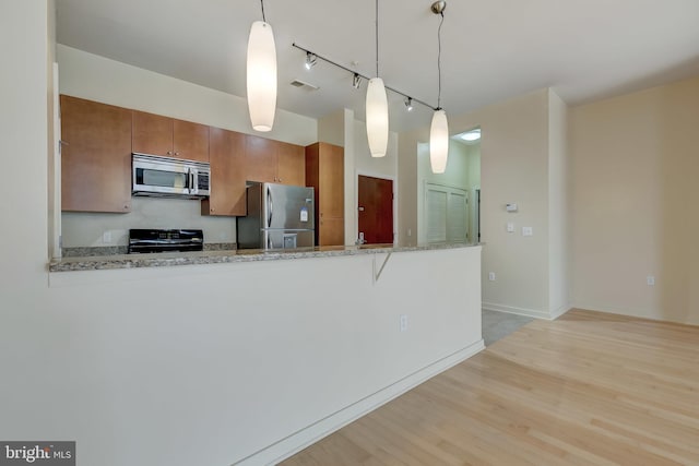 kitchen featuring decorative light fixtures, light stone counters, kitchen peninsula, and stainless steel appliances