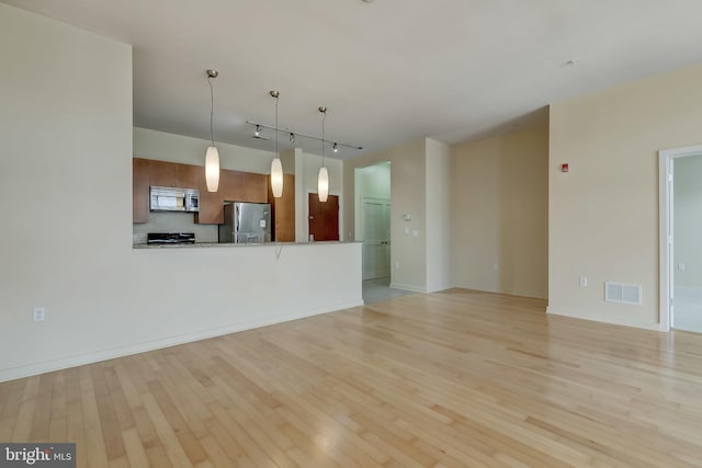 unfurnished living room featuring track lighting and light wood-type flooring