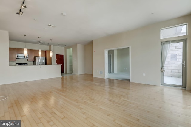 unfurnished living room featuring rail lighting and light wood-type flooring