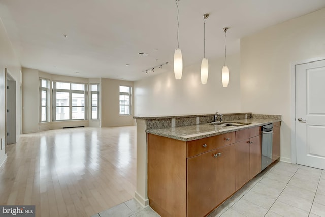 kitchen with kitchen peninsula, light stone counters, sink, pendant lighting, and light tile patterned floors