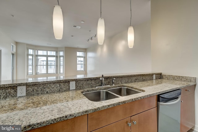 kitchen featuring decorative light fixtures, light stone counters, sink, and track lighting