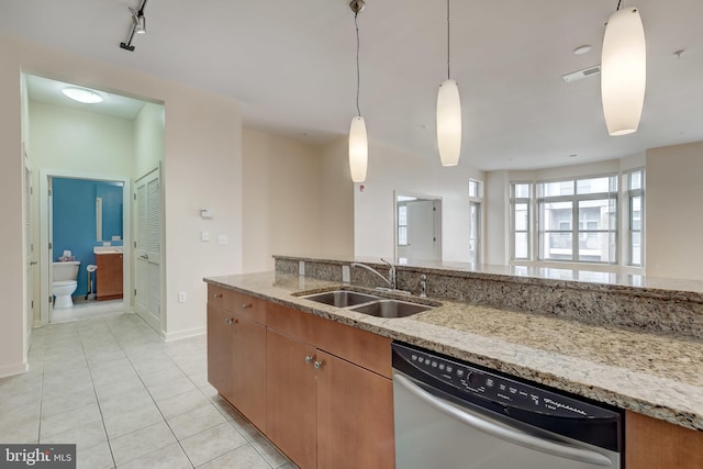 kitchen with rail lighting, light stone counters, sink, light tile patterned floors, and dishwasher