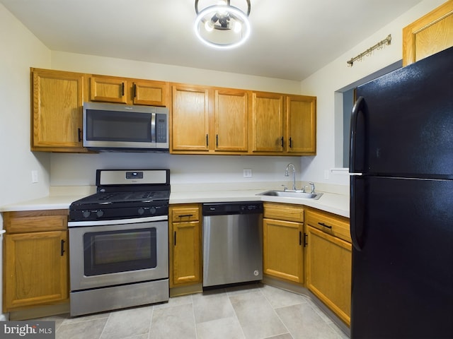 kitchen with appliances with stainless steel finishes, sink, and light tile patterned floors