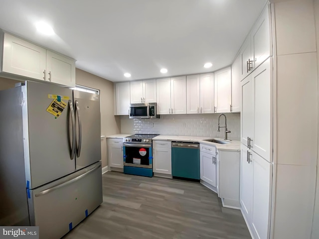 kitchen with light hardwood / wood-style floors, appliances with stainless steel finishes, tasteful backsplash, white cabinets, and sink