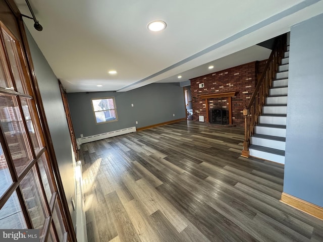 unfurnished living room featuring dark hardwood / wood-style flooring, a brick fireplace, and a baseboard heating unit