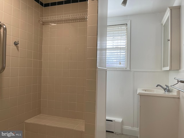 bathroom featuring vanity, baseboard heating, and tiled shower