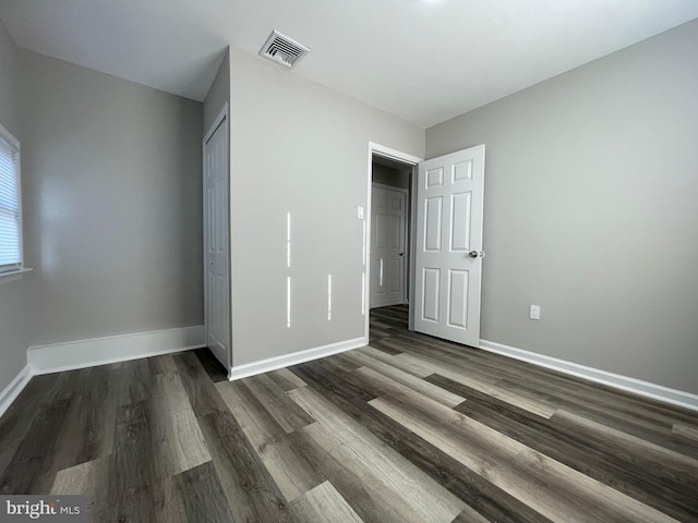 unfurnished bedroom featuring dark hardwood / wood-style flooring and a closet