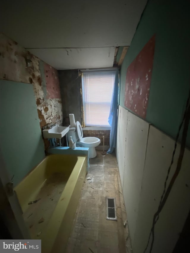 bathroom featuring a bathing tub, toilet, and sink