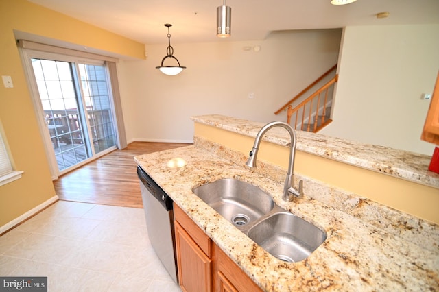 kitchen featuring pendant lighting, dishwasher, light stone counters, and sink