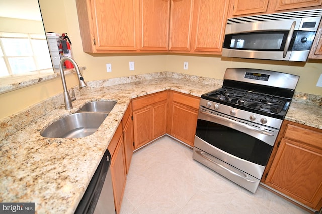 kitchen with sink, light stone countertops, stainless steel appliances, and light tile patterned floors