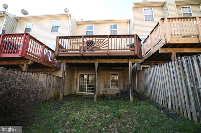 rear view of house with central AC unit, a deck, and a yard