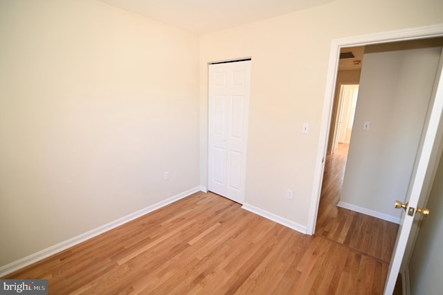 unfurnished bedroom with light wood-type flooring and a closet