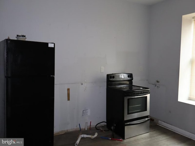 kitchen with electric stove, black fridge, and light hardwood / wood-style flooring