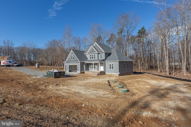 view of front facade featuring dirt driveway and roof with shingles