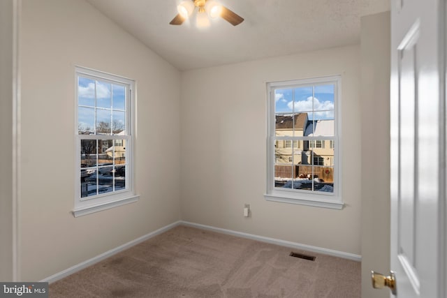 spare room with ceiling fan, visible vents, baseboards, vaulted ceiling, and carpet