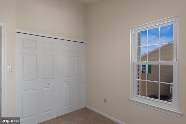 unfurnished bedroom with carpet floors, a closet, and baseboards