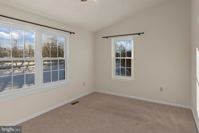 carpeted spare room with visible vents, vaulted ceiling, and baseboards