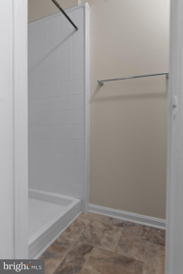 bathroom featuring a tile shower and baseboards