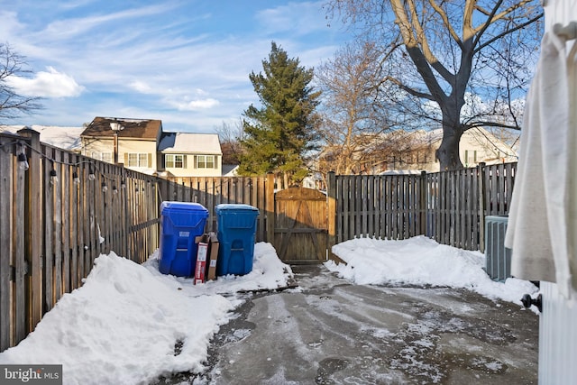 snowy yard with fence private yard, a gate, and cooling unit