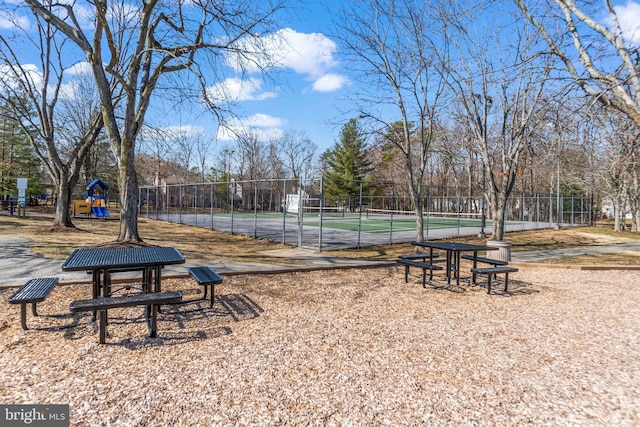 view of community featuring a tennis court, playground community, and fence