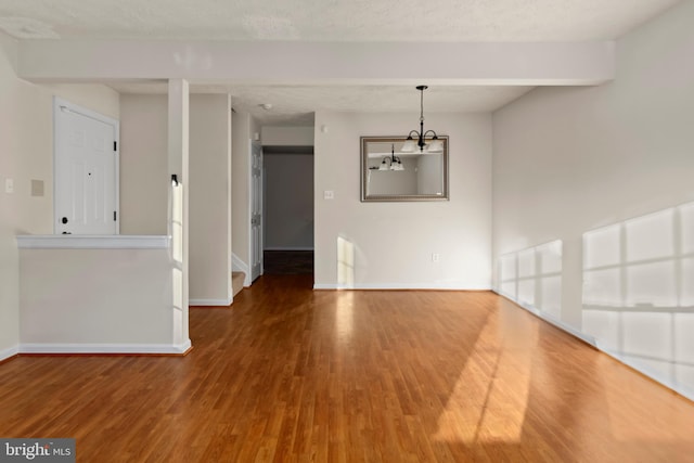 unfurnished dining area with a textured ceiling, baseboards, and wood finished floors