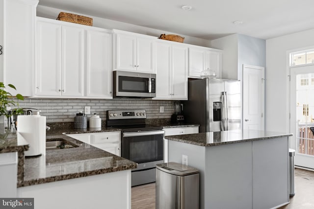 kitchen featuring white cabinets, dark stone countertops, a kitchen island, and appliances with stainless steel finishes