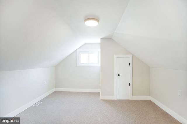 additional living space with light colored carpet and vaulted ceiling