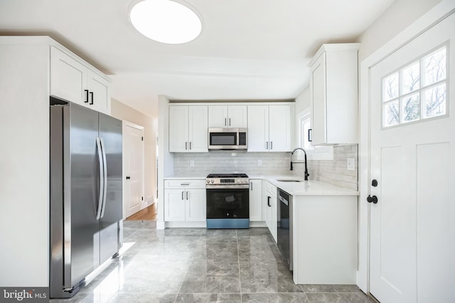 kitchen with decorative backsplash, appliances with stainless steel finishes, white cabinetry, and sink