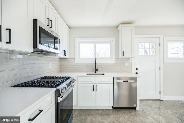 kitchen with decorative backsplash, sink, white cabinets, and appliances with stainless steel finishes