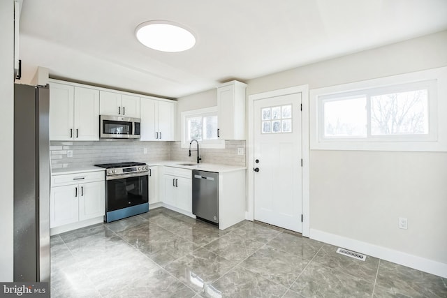 kitchen featuring tasteful backsplash, white cabinetry, sink, and appliances with stainless steel finishes