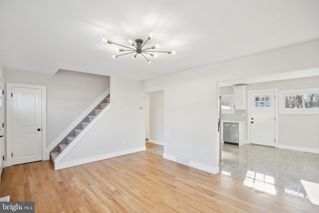 unfurnished living room with a chandelier and light hardwood / wood-style floors