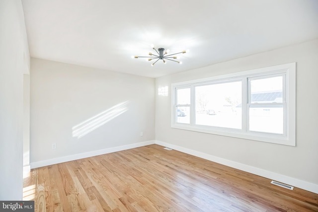 unfurnished room with light hardwood / wood-style flooring and a notable chandelier