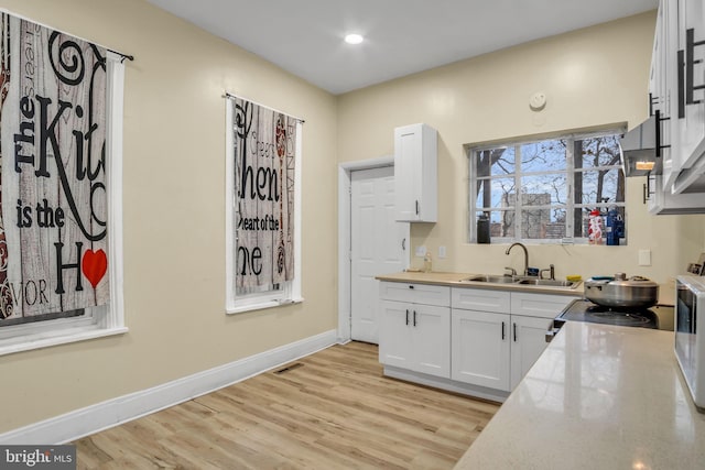 kitchen with white cabinetry, sink, and light hardwood / wood-style flooring