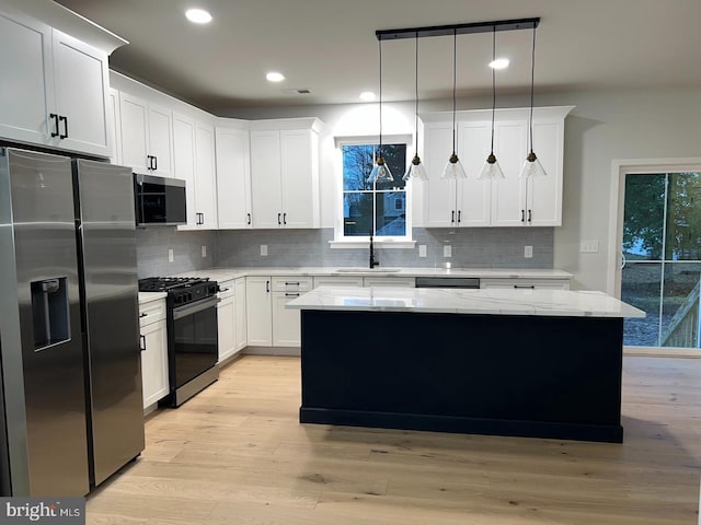 kitchen featuring pendant lighting, a center island, white cabinets, light stone counters, and stainless steel appliances