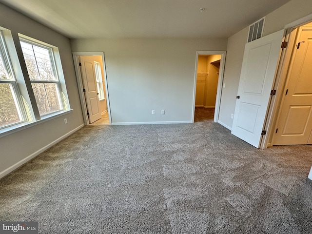 unfurnished bedroom with carpet floors, ensuite bath, and a spacious closet