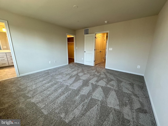 unfurnished bedroom featuring a spacious closet, a closet, carpet floors, and ensuite bathroom