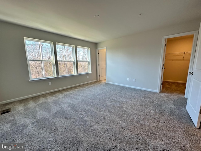 unfurnished bedroom with carpet flooring, a spacious closet, and a closet