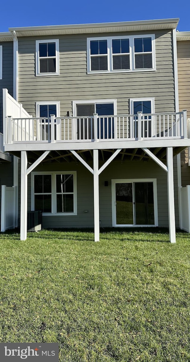 rear view of property featuring a wooden deck and a yard