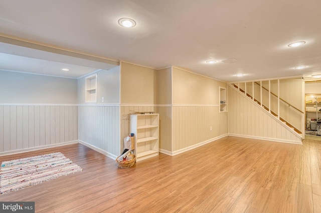 basement with hardwood / wood-style floors and ornamental molding