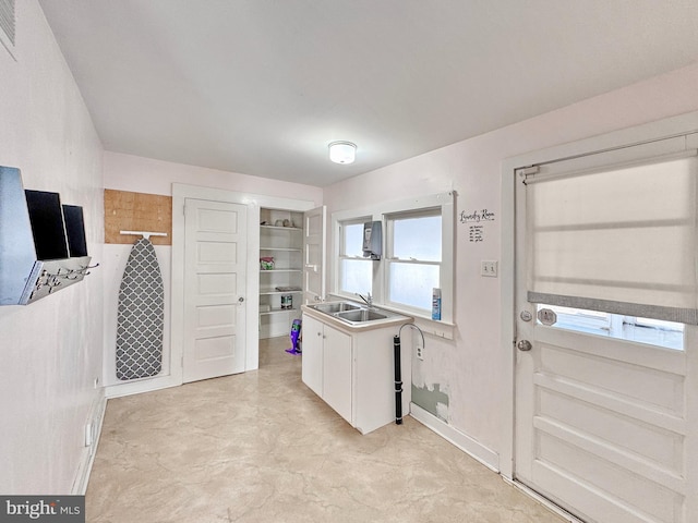 kitchen with white cabinets, built in shelves, and sink