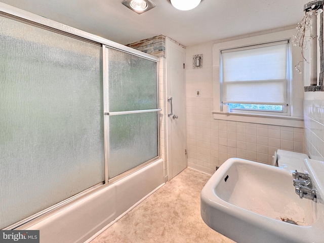 bathroom featuring sink, shower / bath combination with glass door, and tile walls