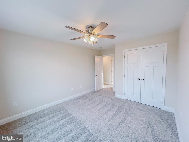 unfurnished bedroom featuring ceiling fan, light carpet, and a closet