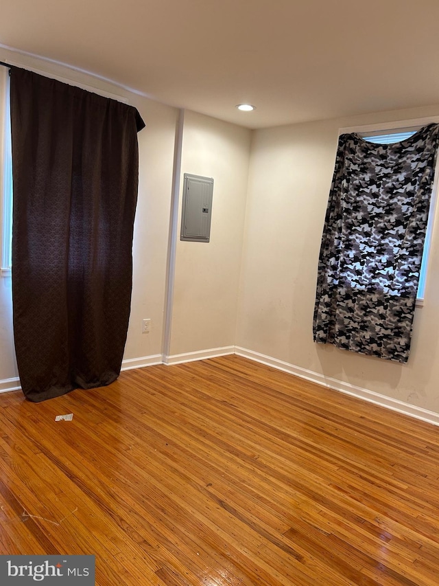 unfurnished room featuring electric panel, baseboards, wood finished floors, and recessed lighting