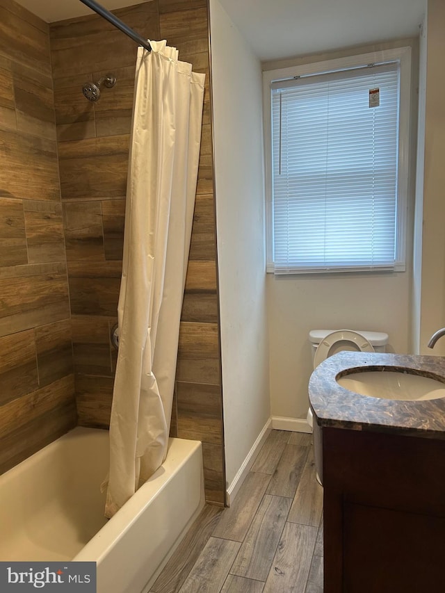 bathroom with baseboards, toilet, wood tiled floor, shower / bath combination with curtain, and vanity