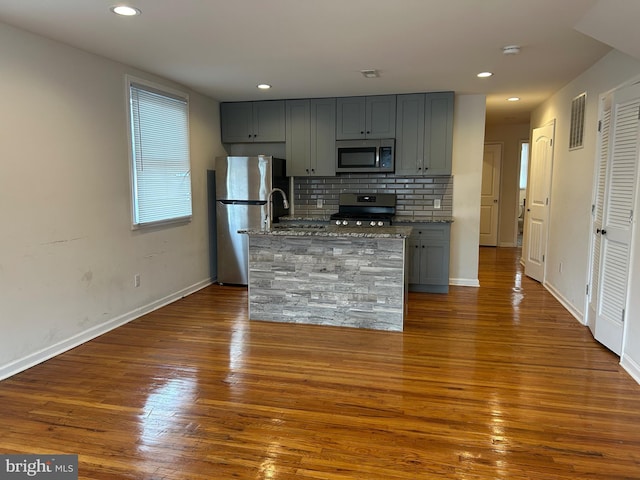 kitchen featuring stone counters, dark wood finished floors, stainless steel appliances, gray cabinets, and visible vents