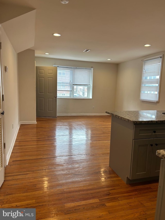 empty room with baseboards, wood finished floors, and recessed lighting