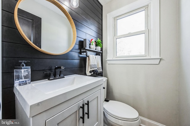 bathroom with wooden walls, vanity, and toilet