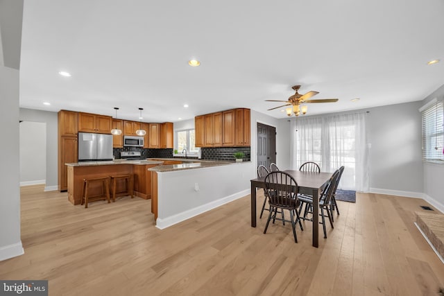 dining room featuring light wood-type flooring, ceiling fan, and sink