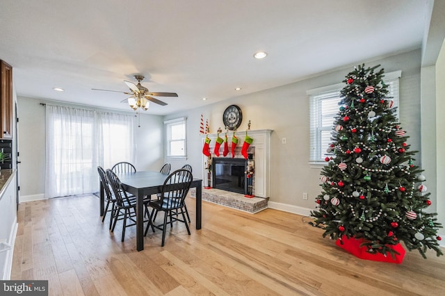 dining area featuring light hardwood / wood-style floors, a brick fireplace, and ceiling fan